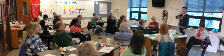 Adults in a classroom setting with whiteboards and sticky notes during an adult class session.