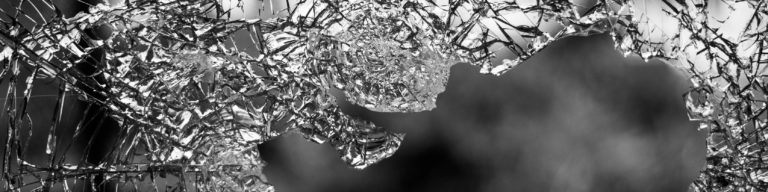 Black and white abstract image of shattered or fragmented glass depicting Capitol violence and destruction.
