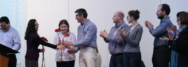 Group of church members standing together indoors clapping and celebrating at a church event.