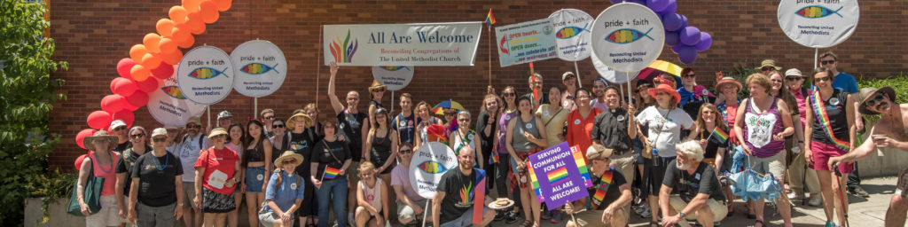 Large group photo of church community members at pride event holding signs reading 'All Are Welcome - Reconciling Congregation of The United Methodist Church' and 'pride + faith' signs, with colorful balloon arch and rainbow pride flags.