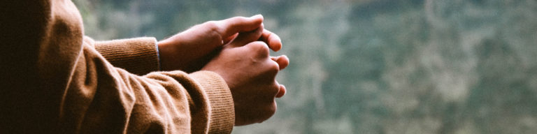 Hands in prayer position wearing a tan cardigan sweater, for Holy Saturday podcast.