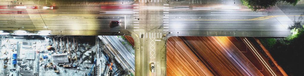 Aerial street intersection view with downtown buildings, urban construction, and traffic crossings - generic cityscape photo.