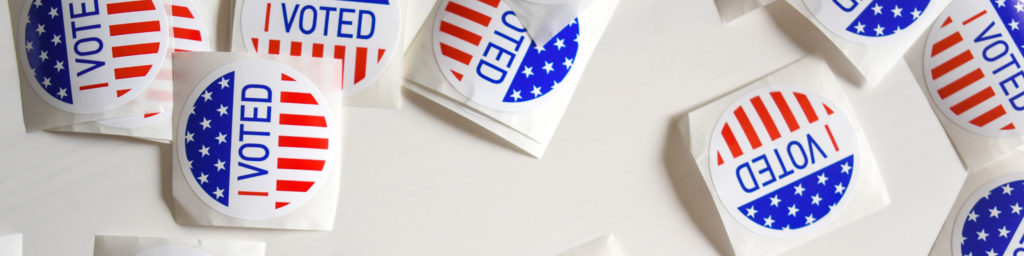 Multiple 'I VOTED' stickers with American flag design in red, white, and blue colors arranged on a white background.