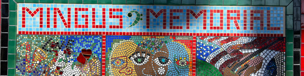 Colorful mosaic mural with pixelated text reading 'MINGLES 2 MEMORIAL' featuring abstract mosaic artwork of faces and patterns.