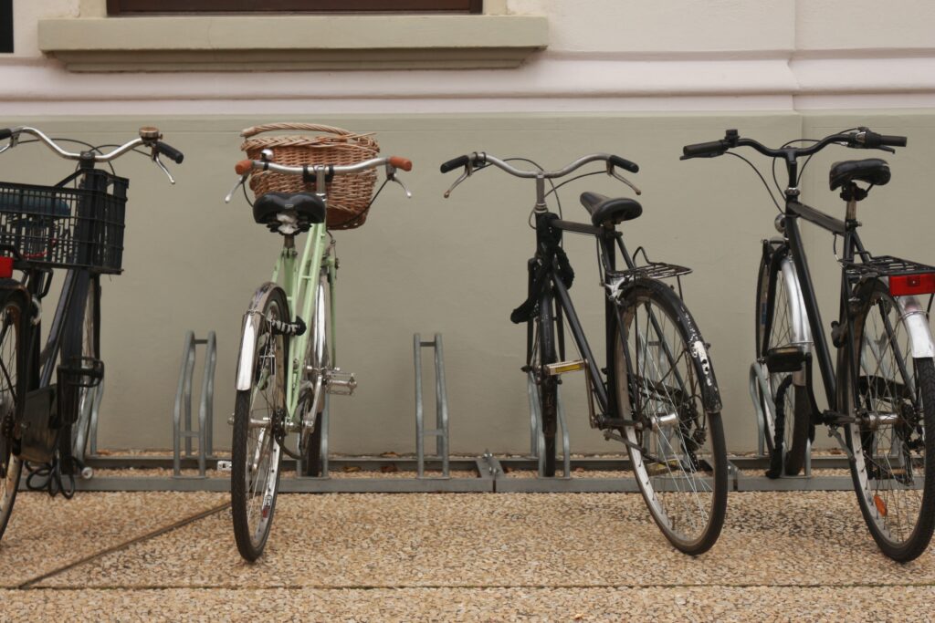 A row of bicycles of different styles parked side by side in an outdoor bike rack.