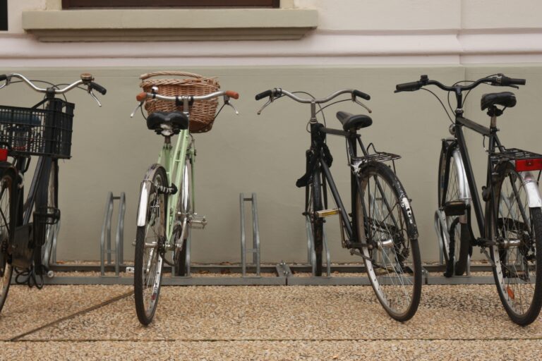 A row of bicycles of different styles parked side by side in an outdoor bike rack.